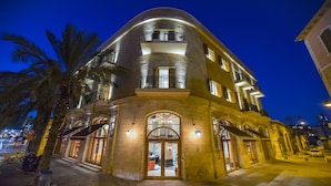 A multi-story hotel with a curved facade, large windows, and a balcony. - Market House - An Atlas Boutique Hotel (Tel Aviv)