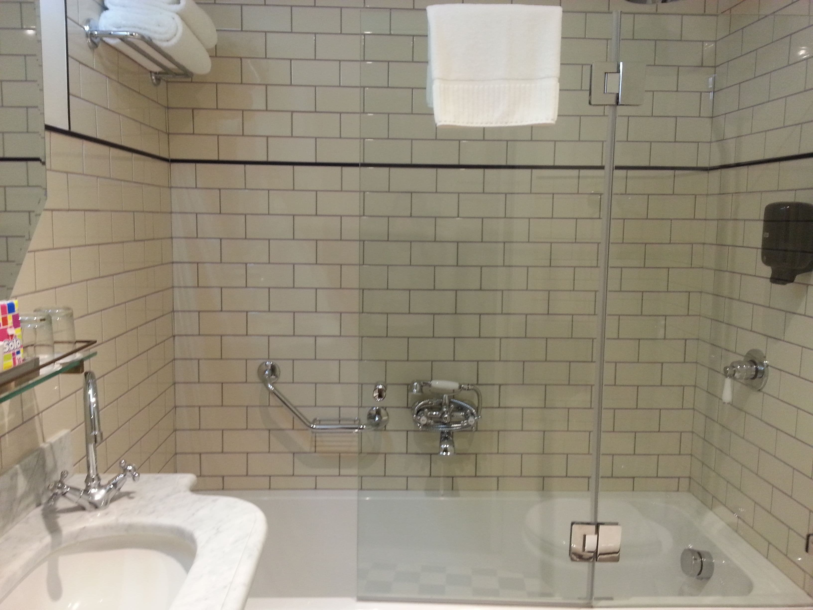 A modern bathroom with a glass-enclosed shower, a marble sink, and a glass shower door.