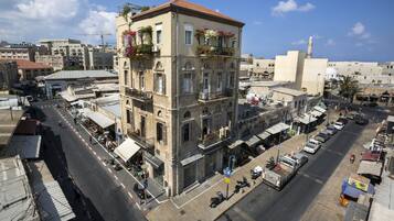 Un edificio de varios pisos con balcones, una calle al frente y una mezquita en el fondo.