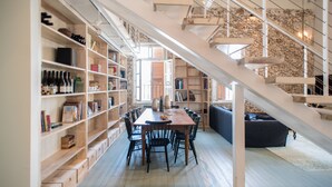 A spacious dining area with a long table and chairs, surrounded by bookshelves and a staircase. - Market House - An Atlas Boutique Hotel (Tel Aviv)