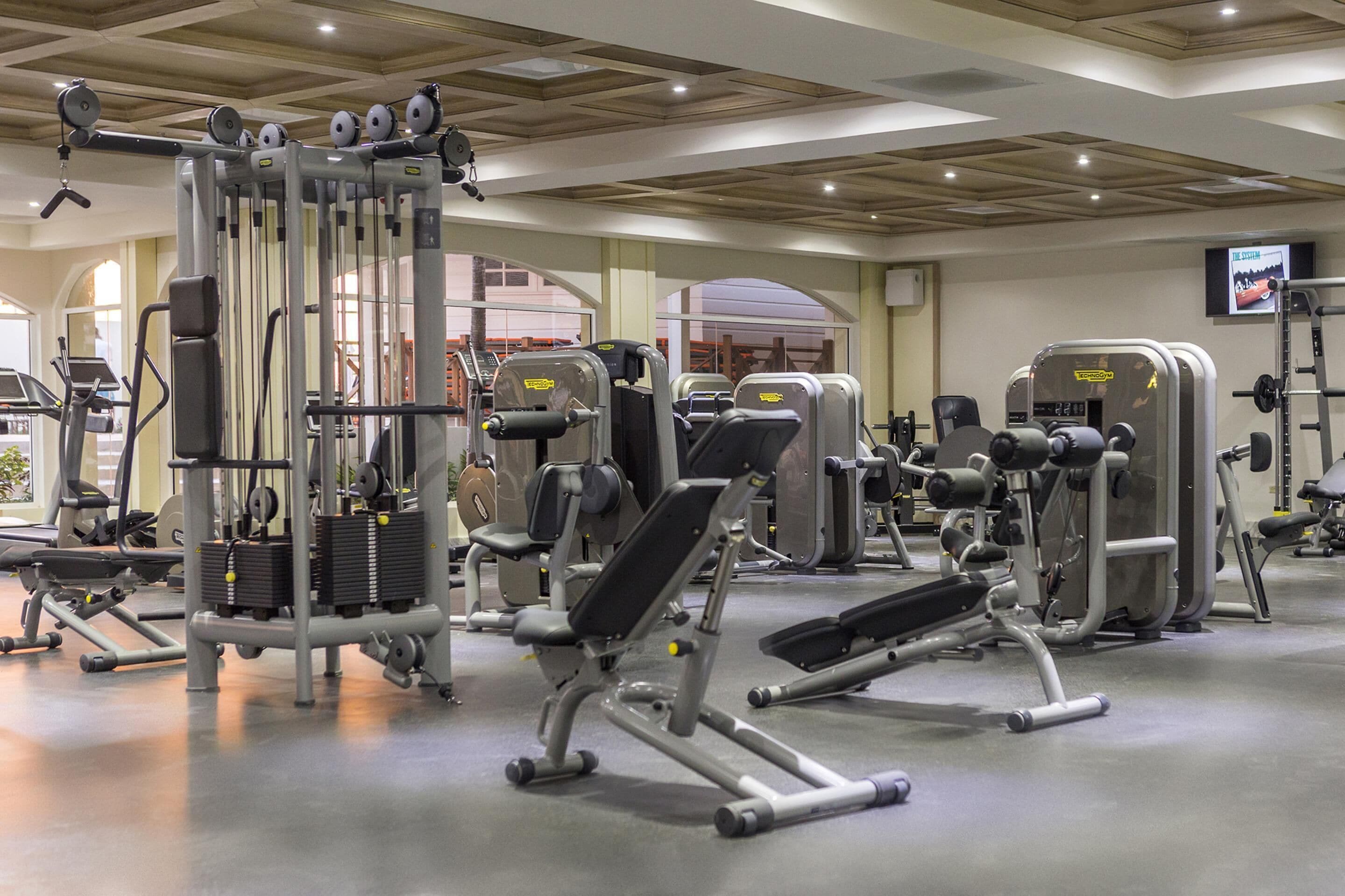 Une salle de sport équipée de divers appareils d’entraînement, notamment des bancs de musculation et un support à squats.