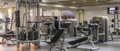 Une salle de sport équipée de divers appareils d’entraînement, notamment des bancs de musculation et un support à squats.