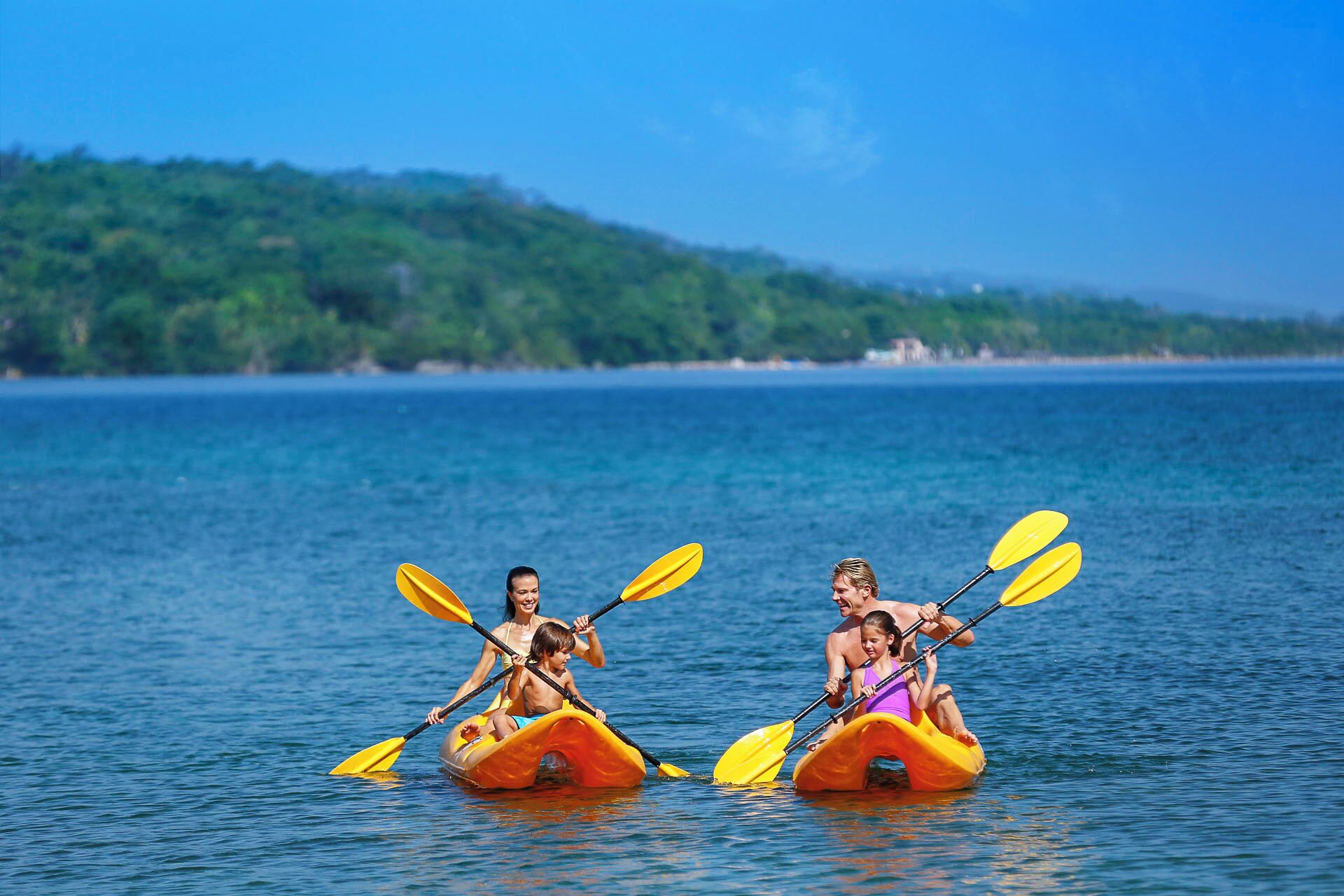Two kayaks on calm water with a forested shoreline in the background.