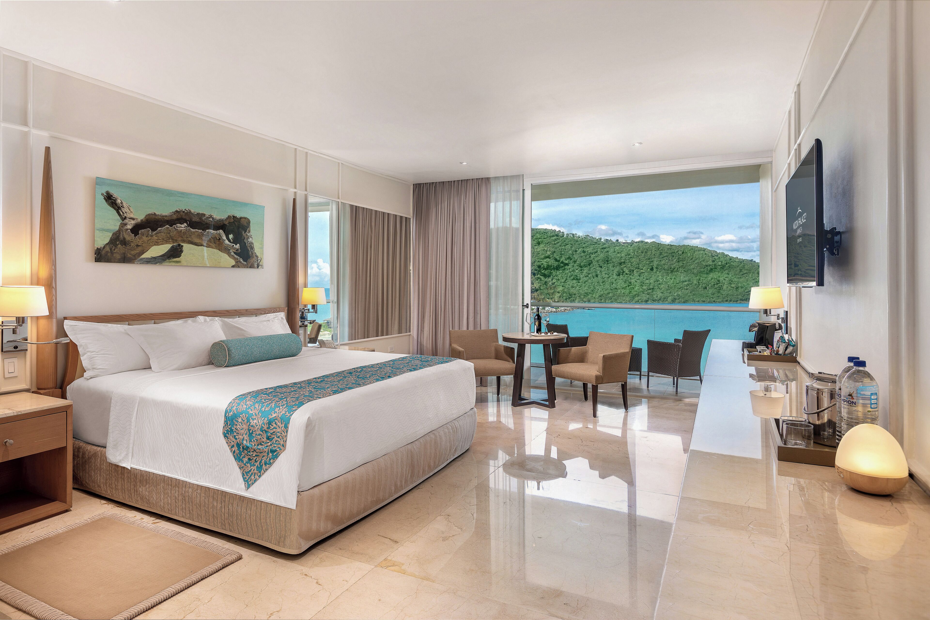 Ein Hotelzimmer mit Bett, Schreibtisch, Stuhl, Tisch und Meerblick.