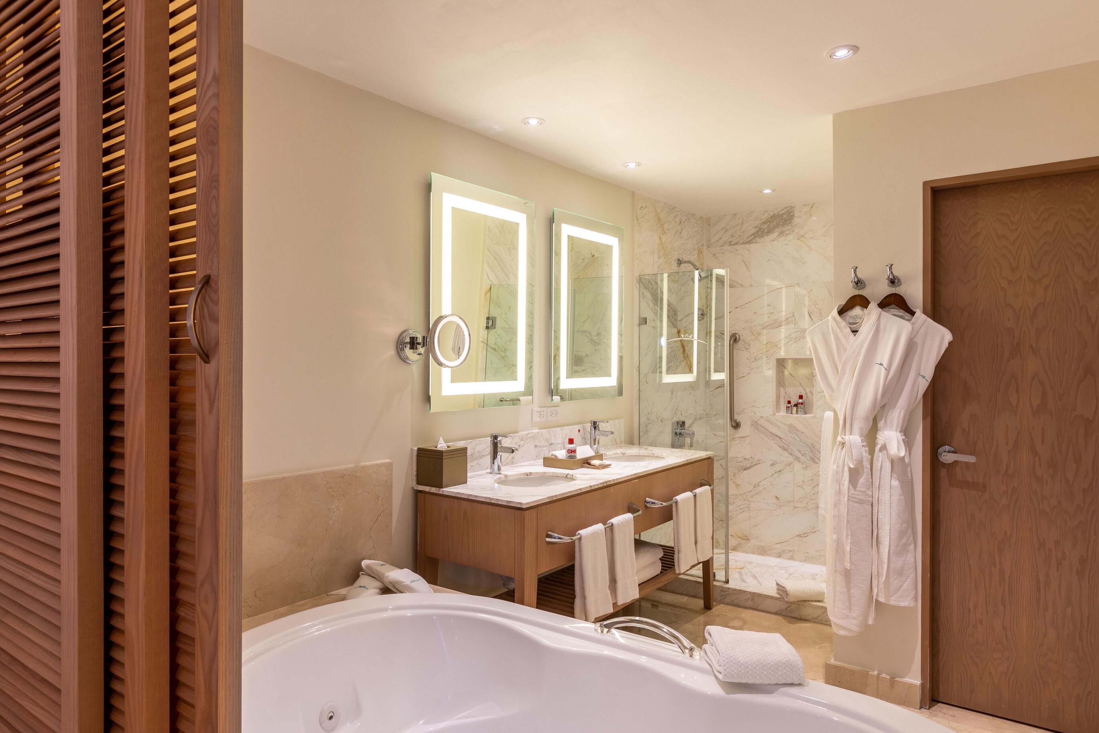 A modern bathroom with a large bathtub, double sinks, and a glass shower enclosure.