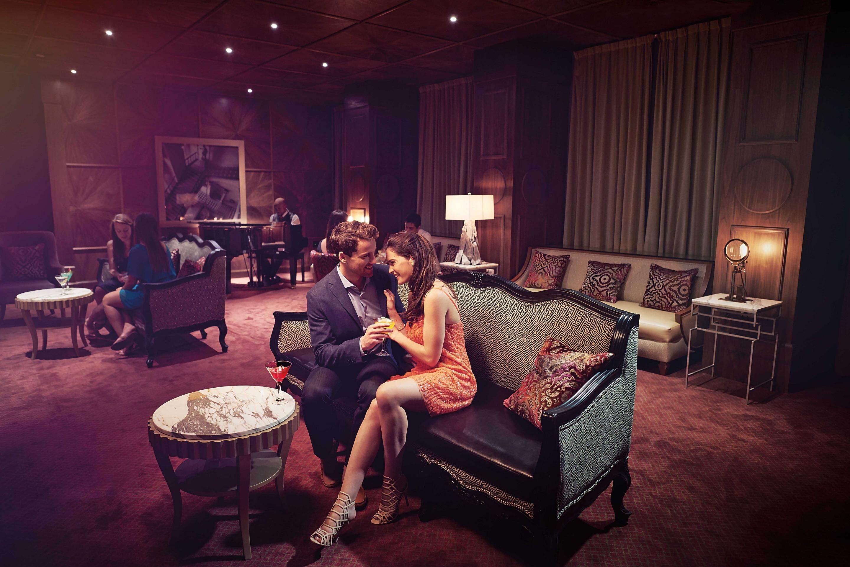 A dimly lit lounge area with a sofa, chairs, and tables.