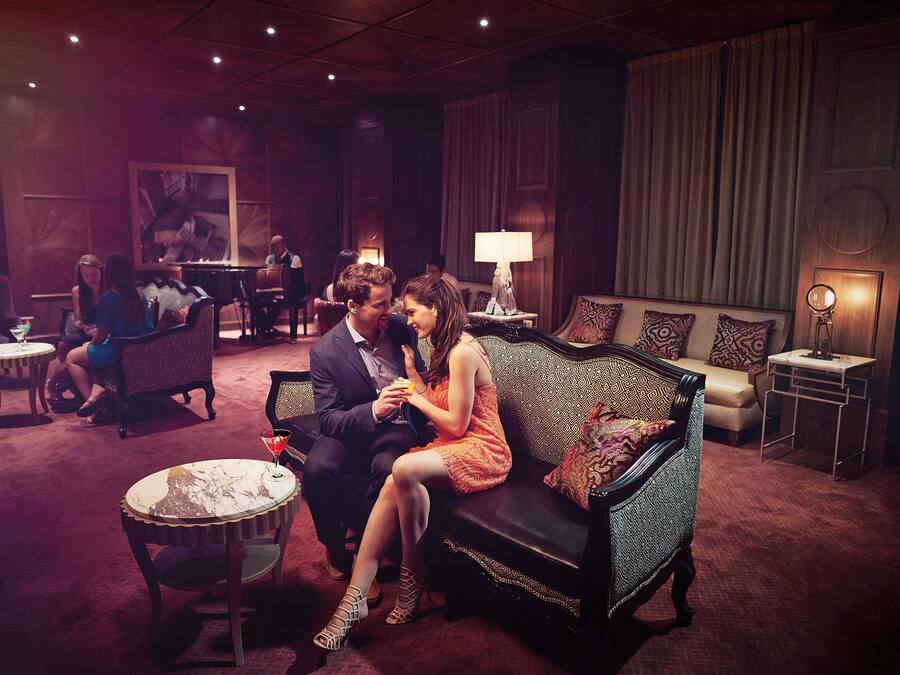 A dimly lit lounge area with a sofa, chairs, and tables.