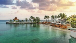 A resort with a pool, lounge chairs, palm trees, and a gazebo by the water. - Moon Palace Jamaica – All Inclusive (Ocho Rios)