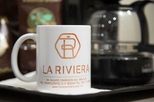Una taza blanca con el texto "LA RIVIERA" e información de contacto.
