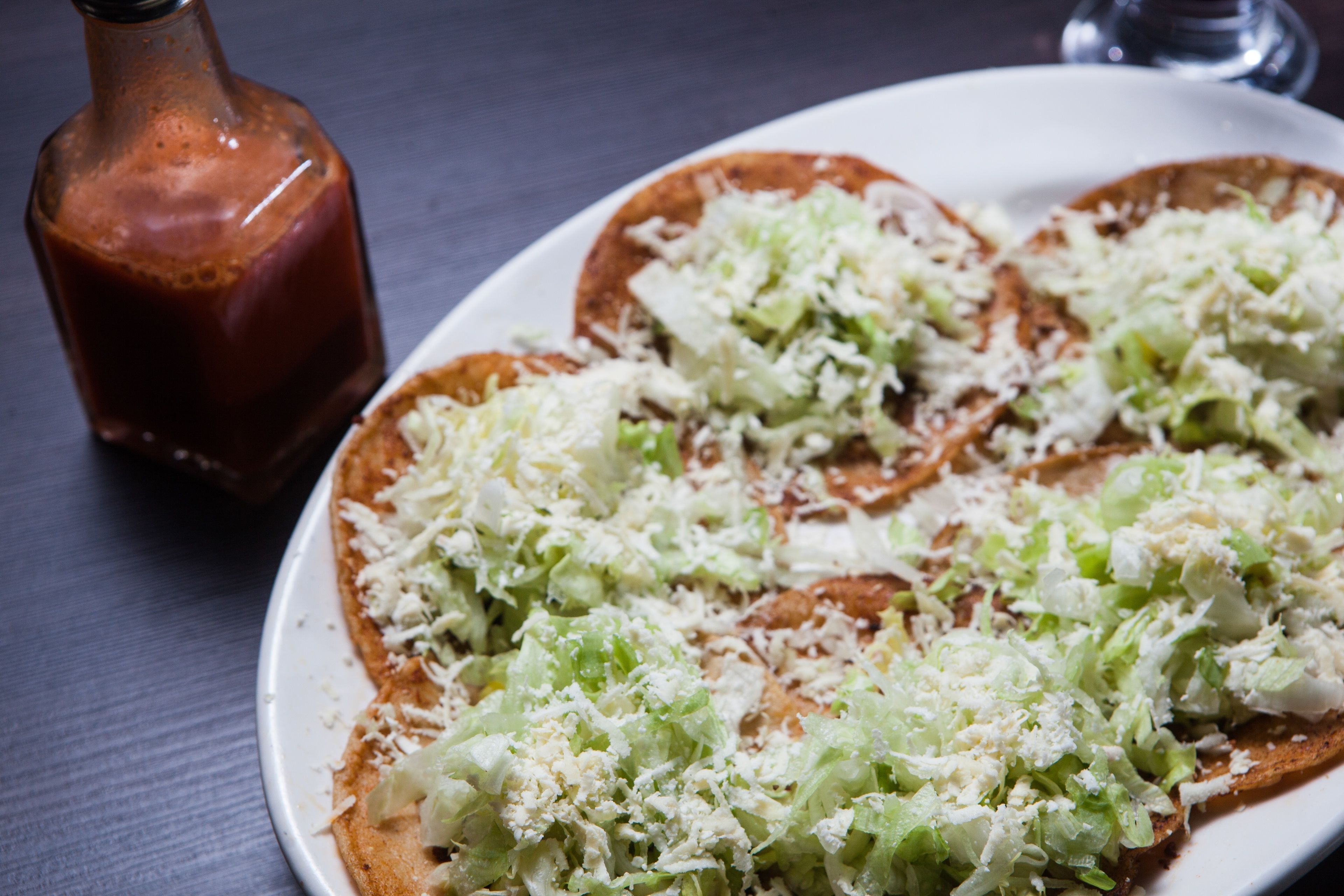 A plate of food with shredded lettuce and a bottle of sauce.