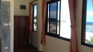 A hallway with a wooden wardrobe, a small window with curtains, and a view of a beach. - Seaview Rainbow (Ko Pha-ngan)