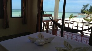 A room with a view of the beach, a hammock, and a table with towels. - Seaview Rainbow (Ko Pha-ngan)
