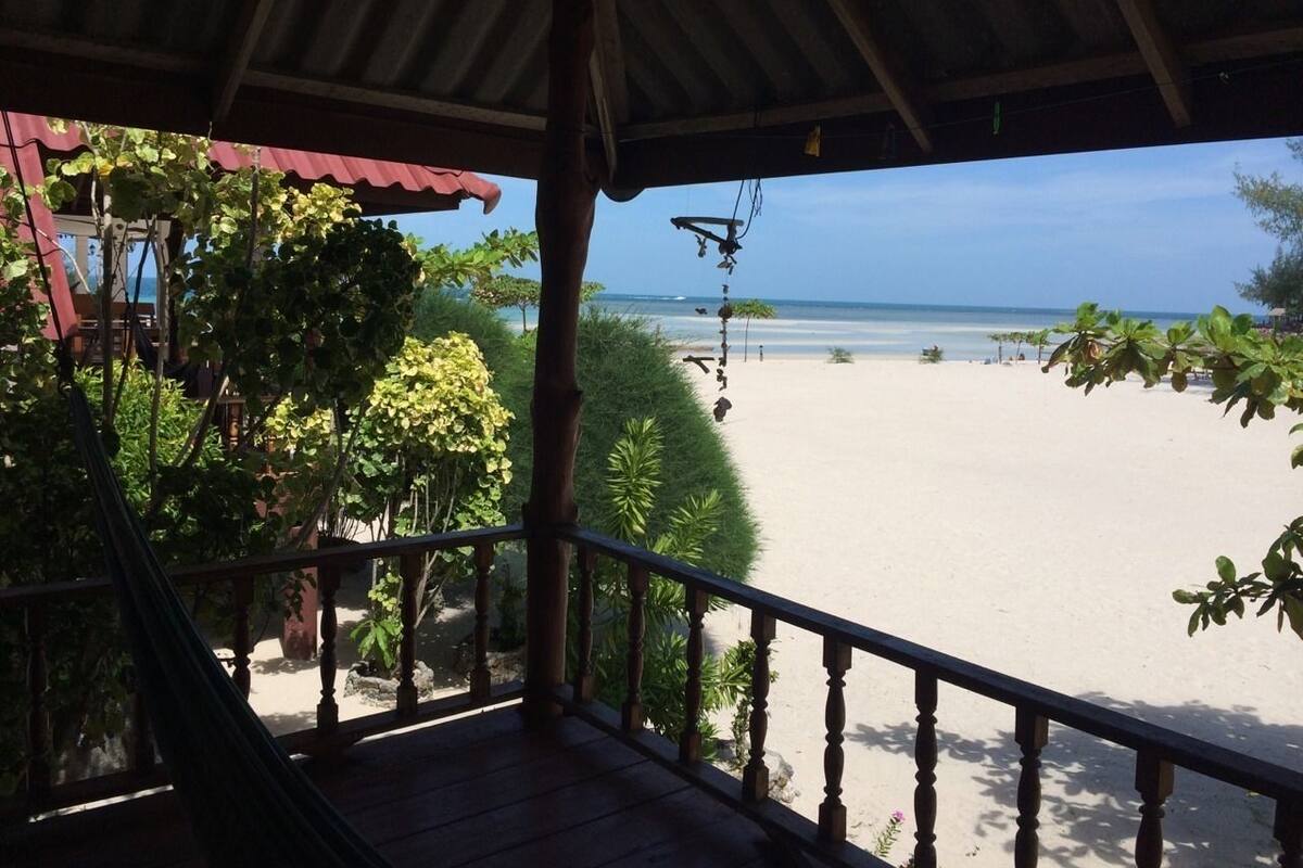 A wooden deck overlooking a beach with a clear view of the ocean.