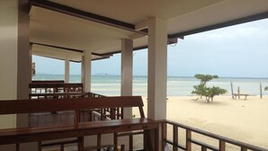 A beachside restaurant with wooden benches and a view of the ocean. - Seaview Rainbow (Ko Pha-ngan)