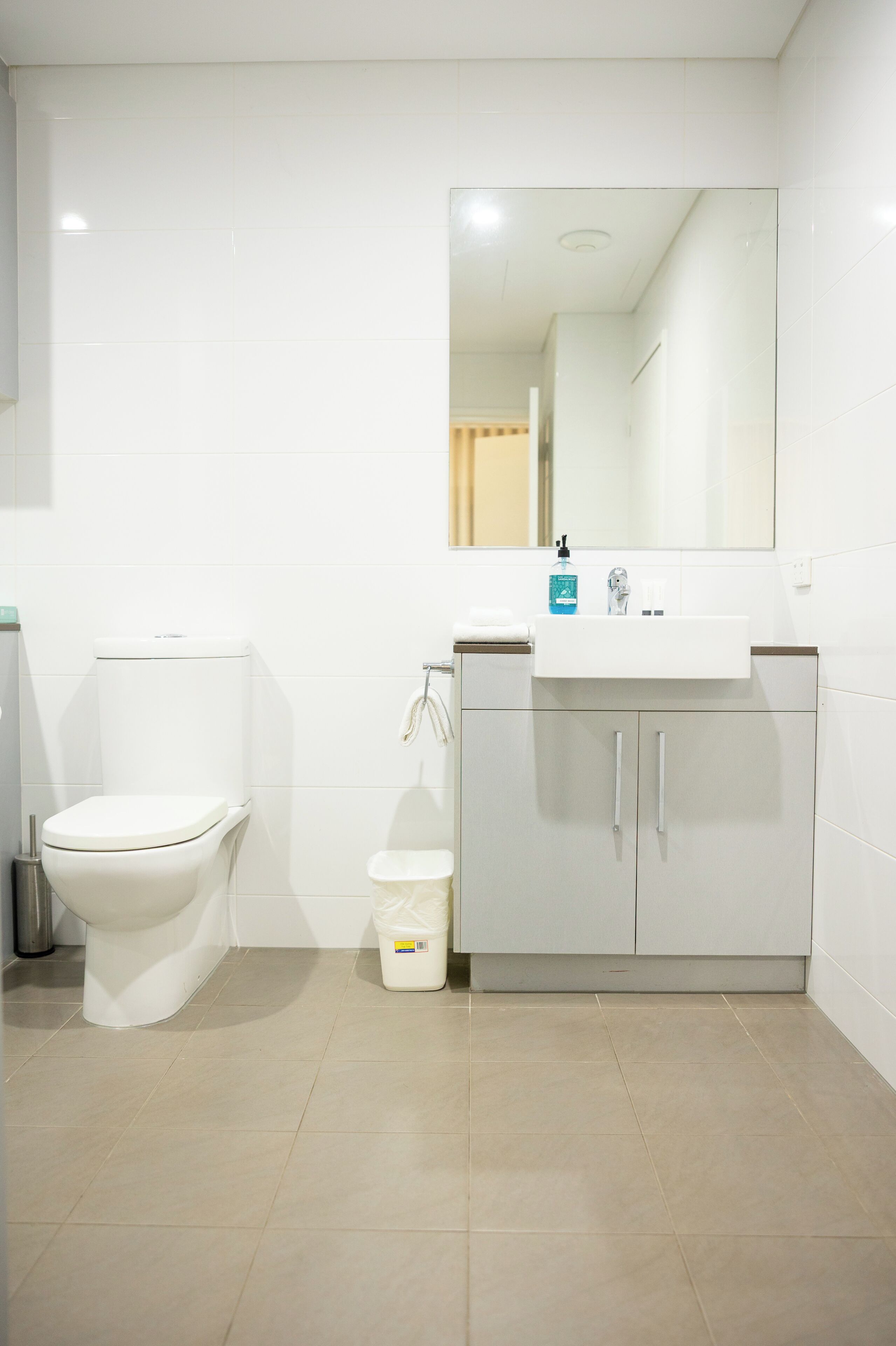 A bathroom with a toilet, sink, mirror, and cabinet.