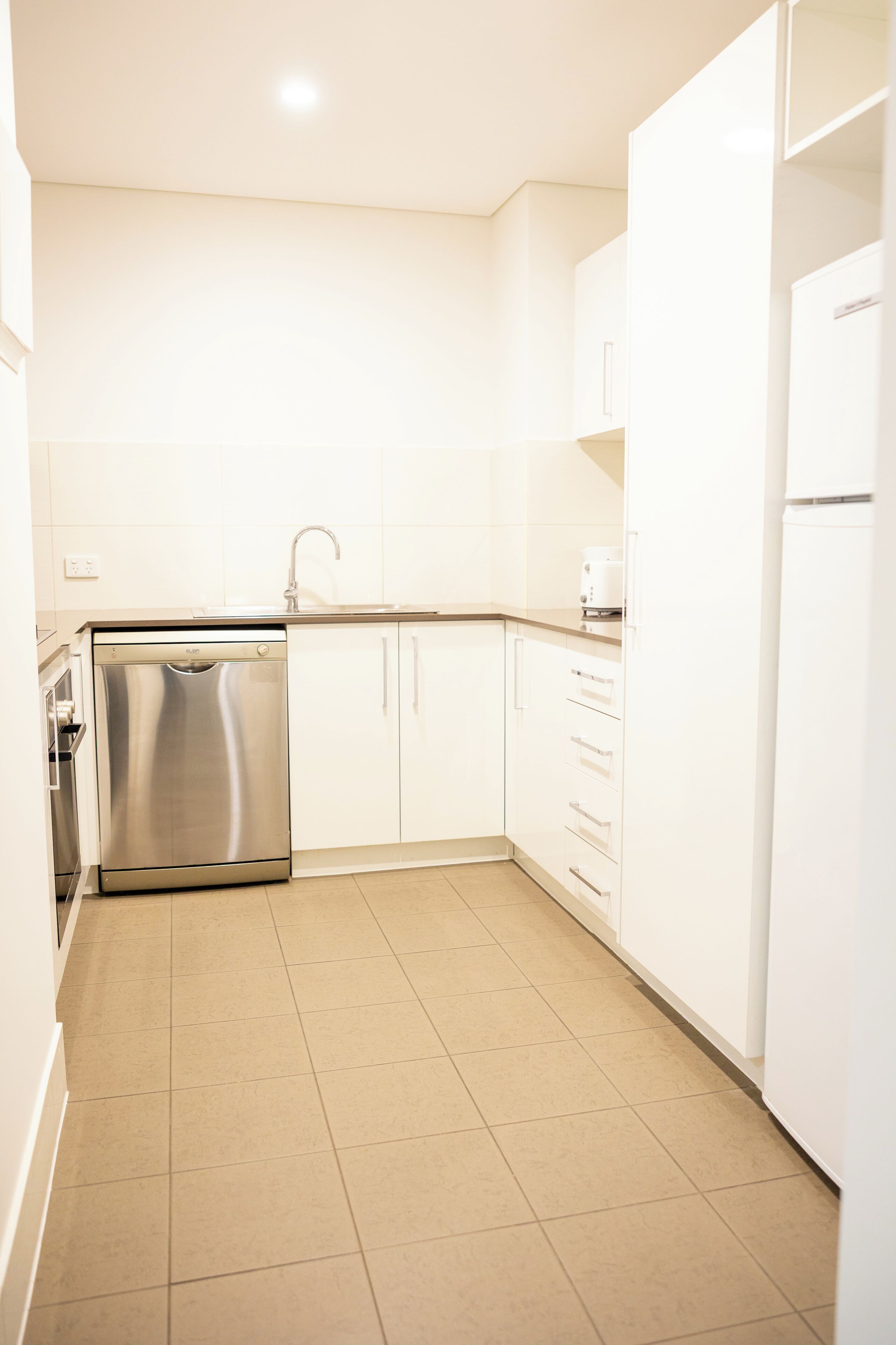 A kitchen with white cabinets, a stainless steel dishwasher, and a sink.