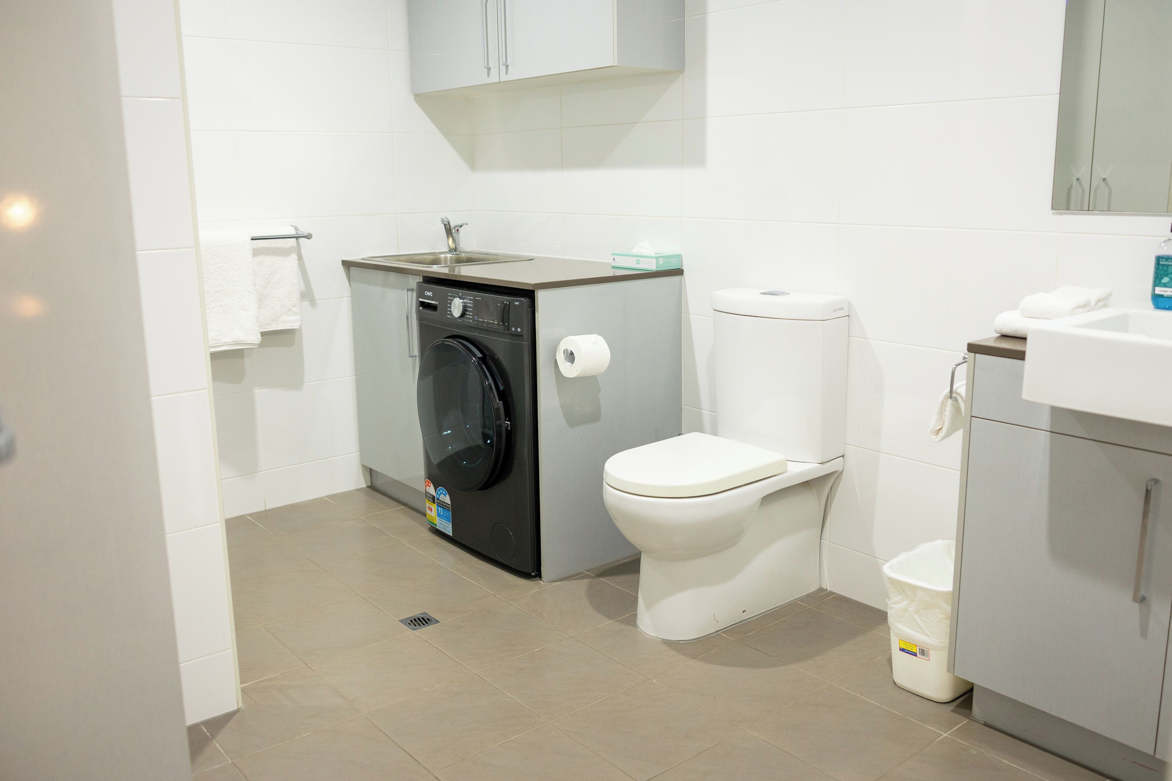 Un baño pequeño con lavadora, inodoro y un lavabo.
