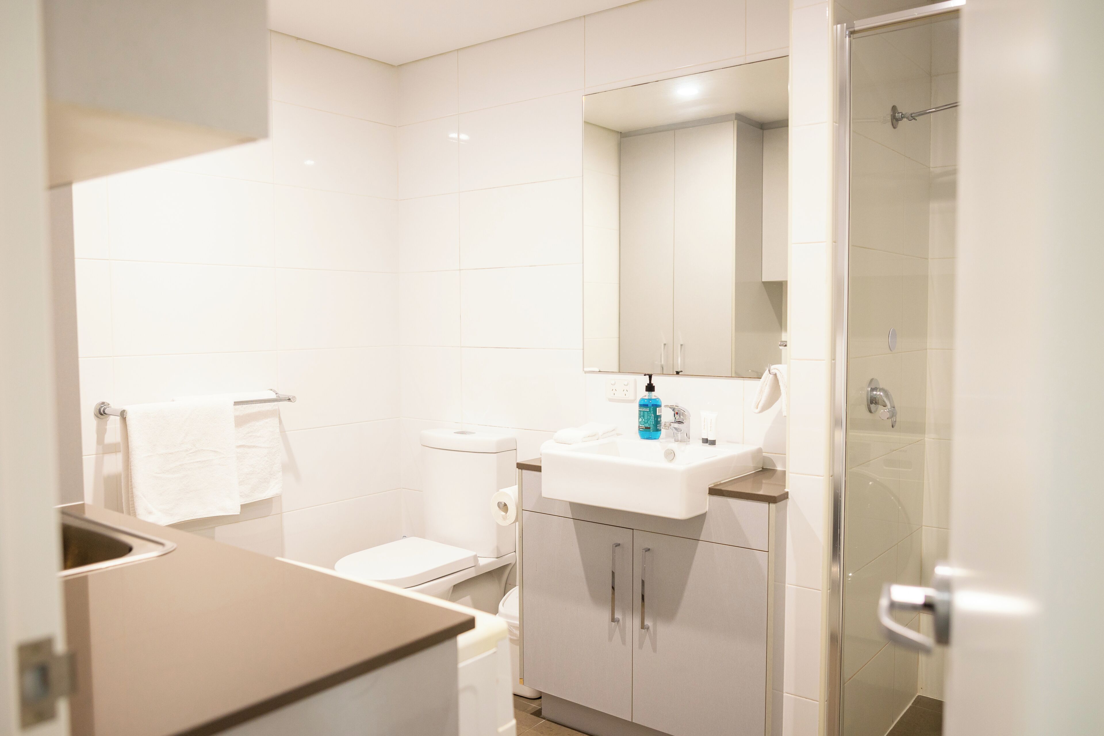 Un bagno moderno con il water, lavandino, specchio e doccia.