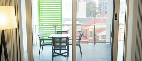 A room with a sliding glass door leading to an outdoor balcony with a table and chairs.
