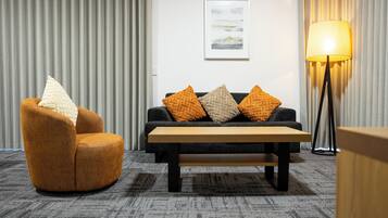 A modern living room with a sofa, armchair, and a standing lamp.