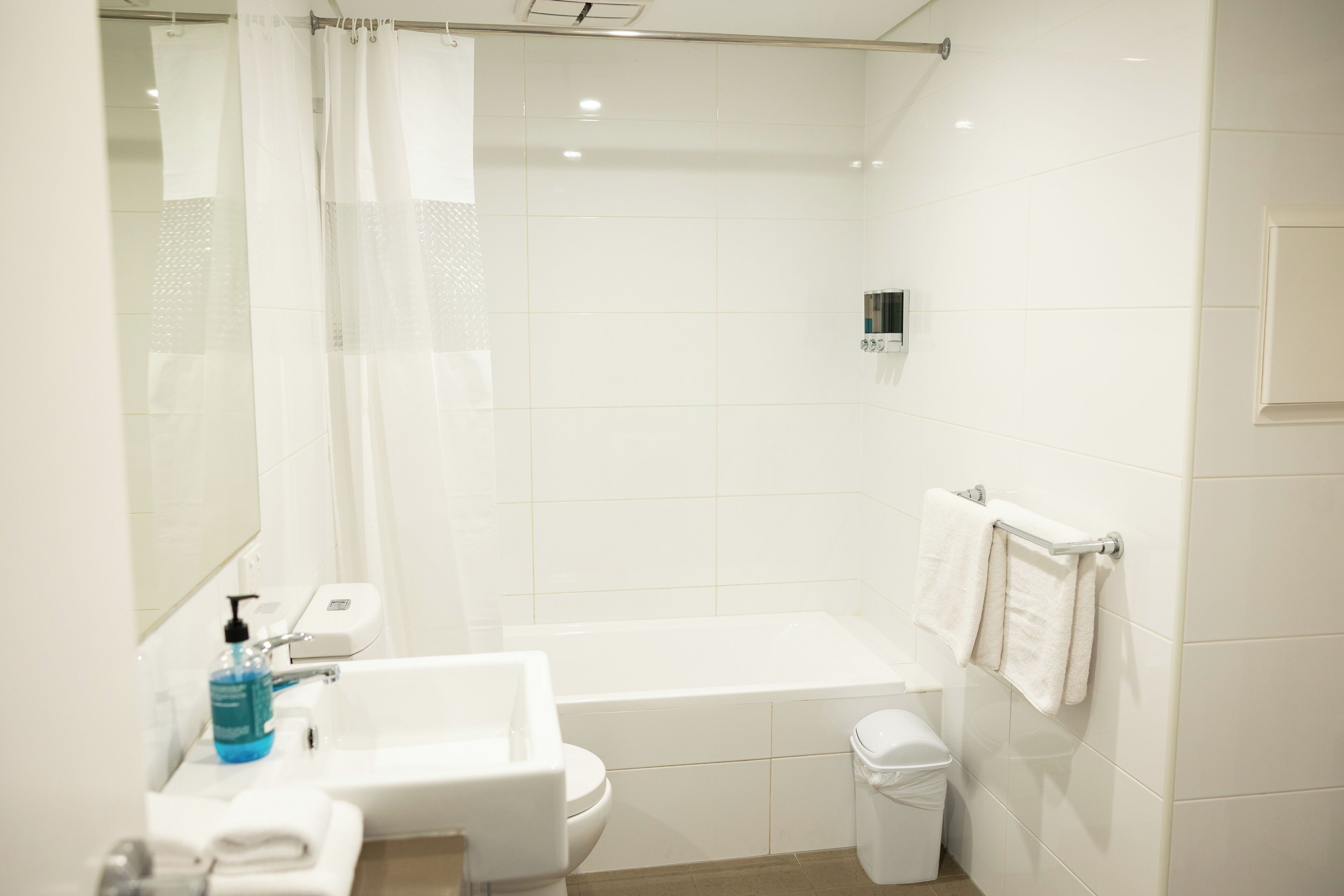 Une salle de bain moderne équipée d’une baignoire, de toilettes, d’un lavabo et d’un porte-serviettes.