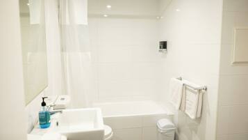 Une salle de bain moderne équipée d’une baignoire, de toilettes, d’un lavabo et d’un porte-serviettes.