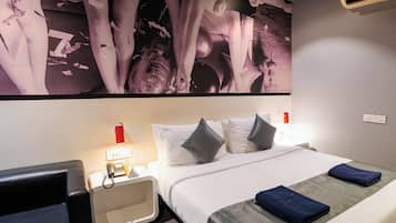 Habitación de hotel con una cama grande, una mesita de noche con lámpara, un teléfono y un aire acondicionado de pared.