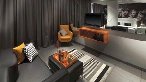 A modern living room with a sofa, armchairs, a coffee table, and a TV. - SinQ Party Hotel (Candolim)