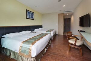 Una habitación de hotel con dos camas, una silla de madera, un escritorio y un televisor.