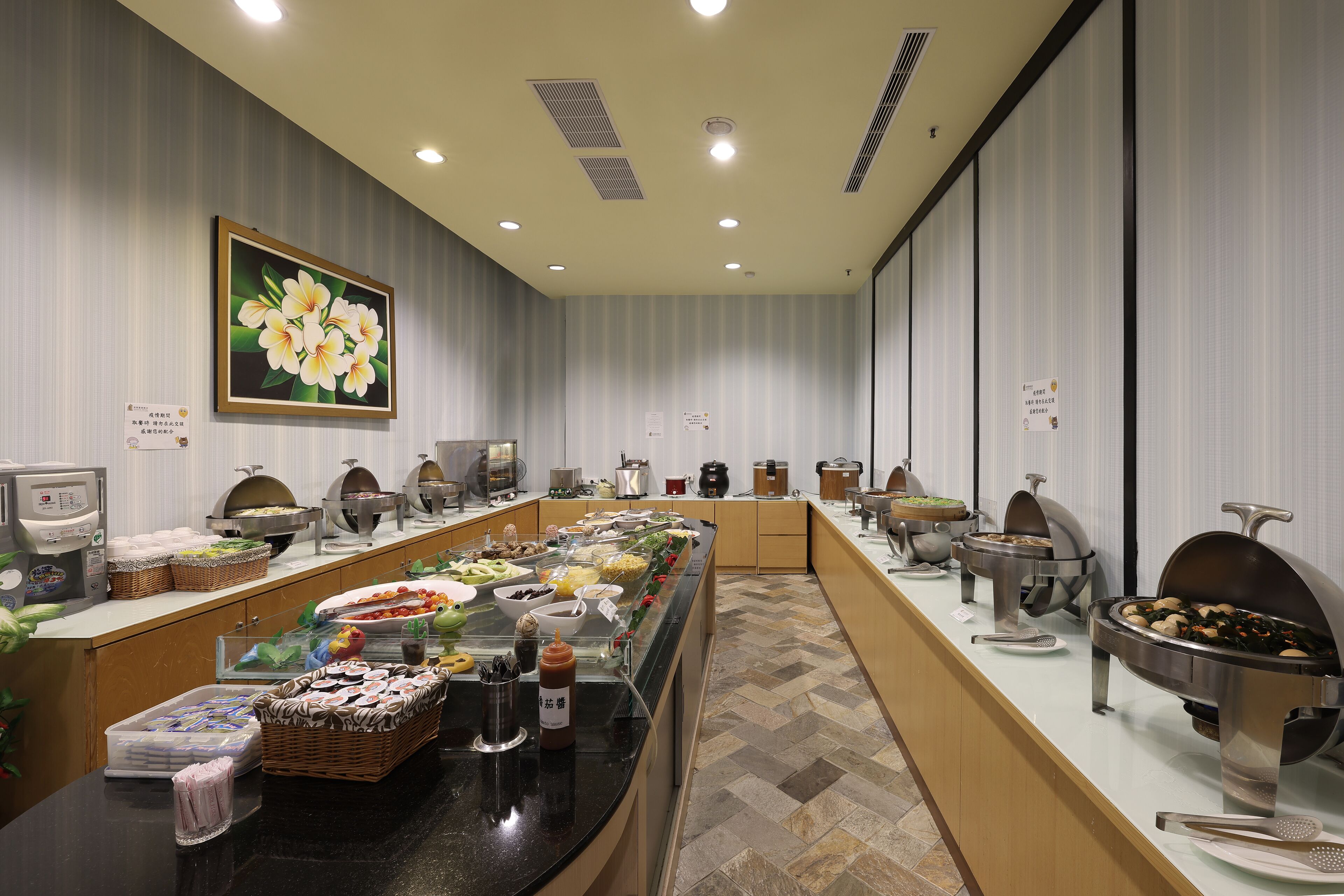 Un espace buffet avec différents stands de nourriture, un tableau accroché au mur et un sol carrelé.