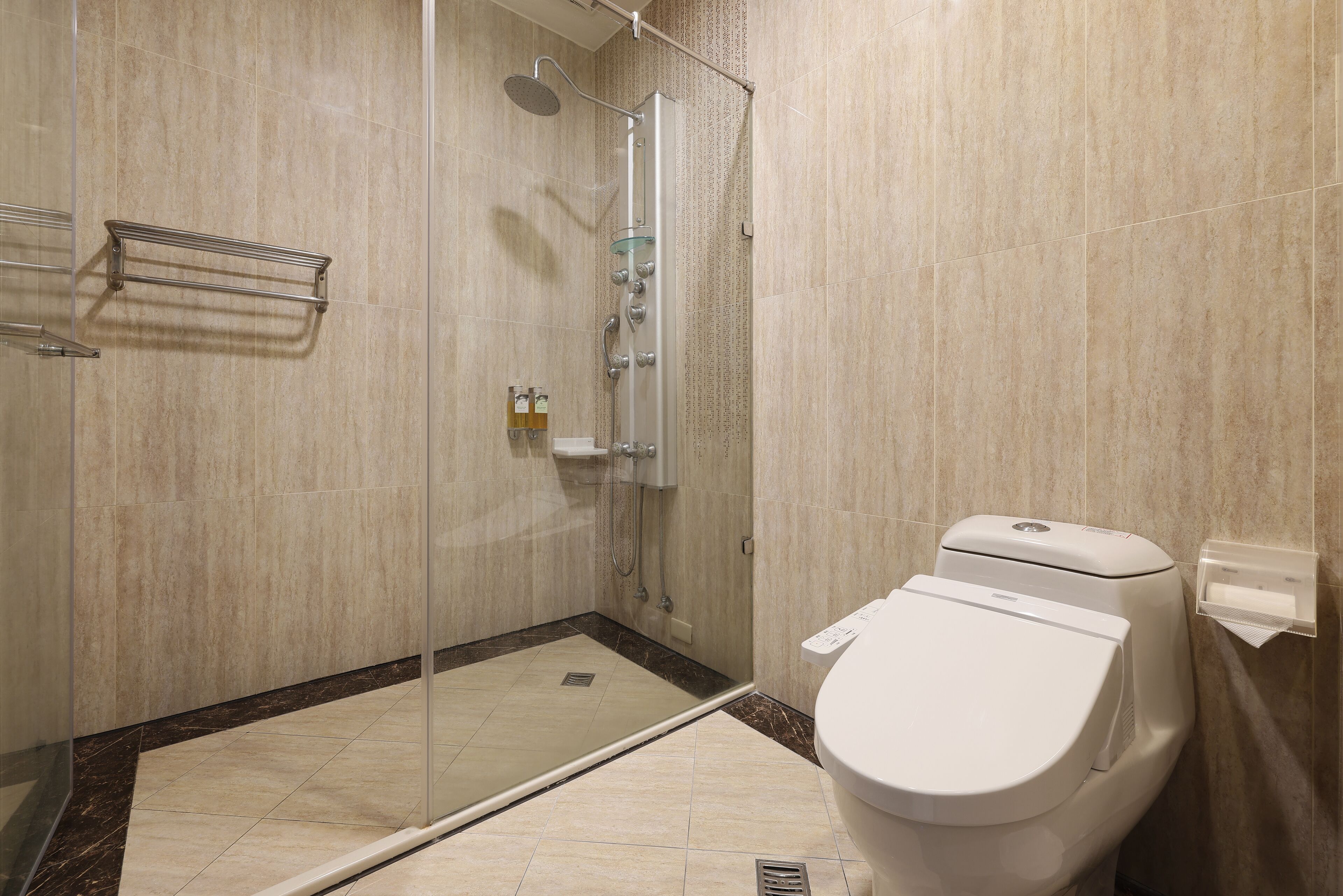 A modern bathroom with a glass-enclosed shower, a toilet, and a towel rack.