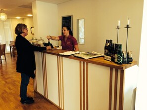 A reception area with a wooden counter, a chalkboard menu, and a selection of beer bottles.