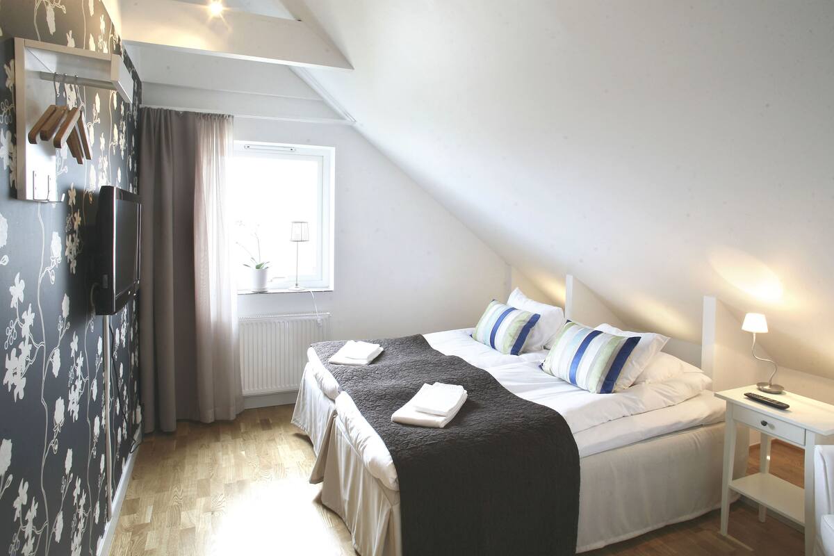 A bedroom with a bed, bedside table, and a window.