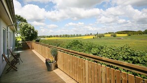 A wooden deck with a view of a green field and a wooden fence. - Nötesjö Hotell (Svedala)