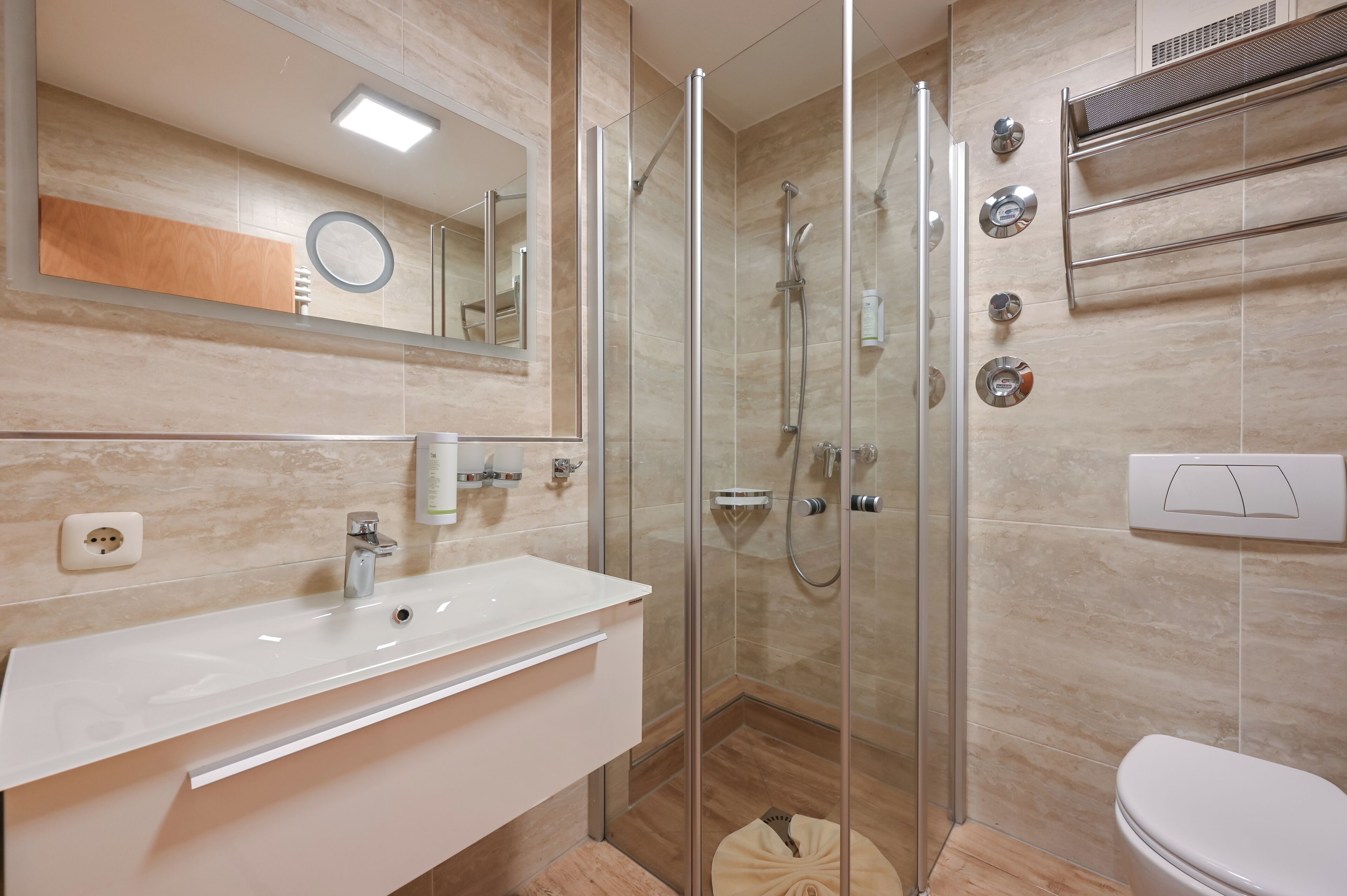 Ein modernes Badezimmer mit einer Duschkabine, einem weißen Waschbecken und einer Toilette.