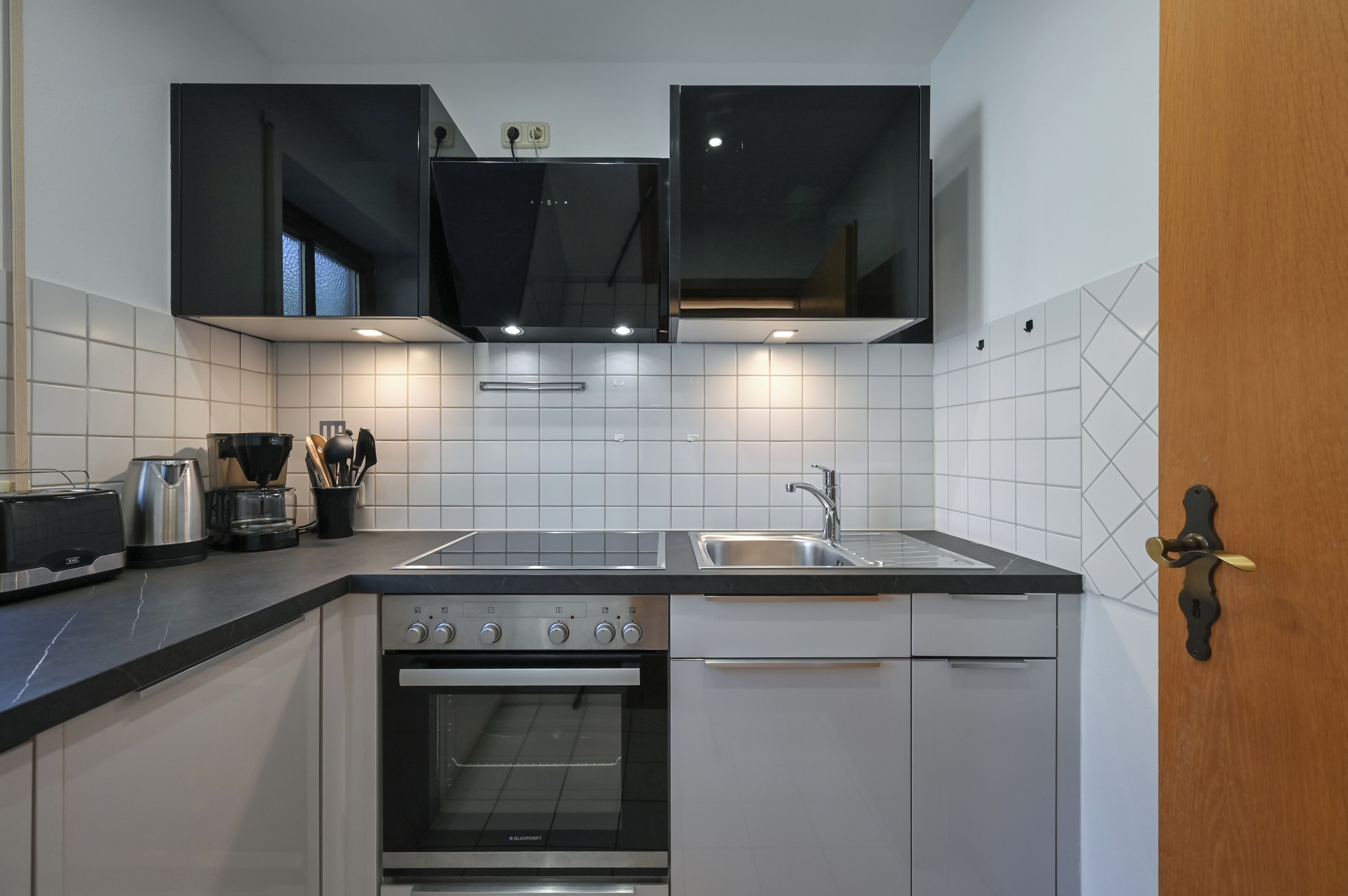 A modern kitchen with a built-in oven, a sink, and a toaster.