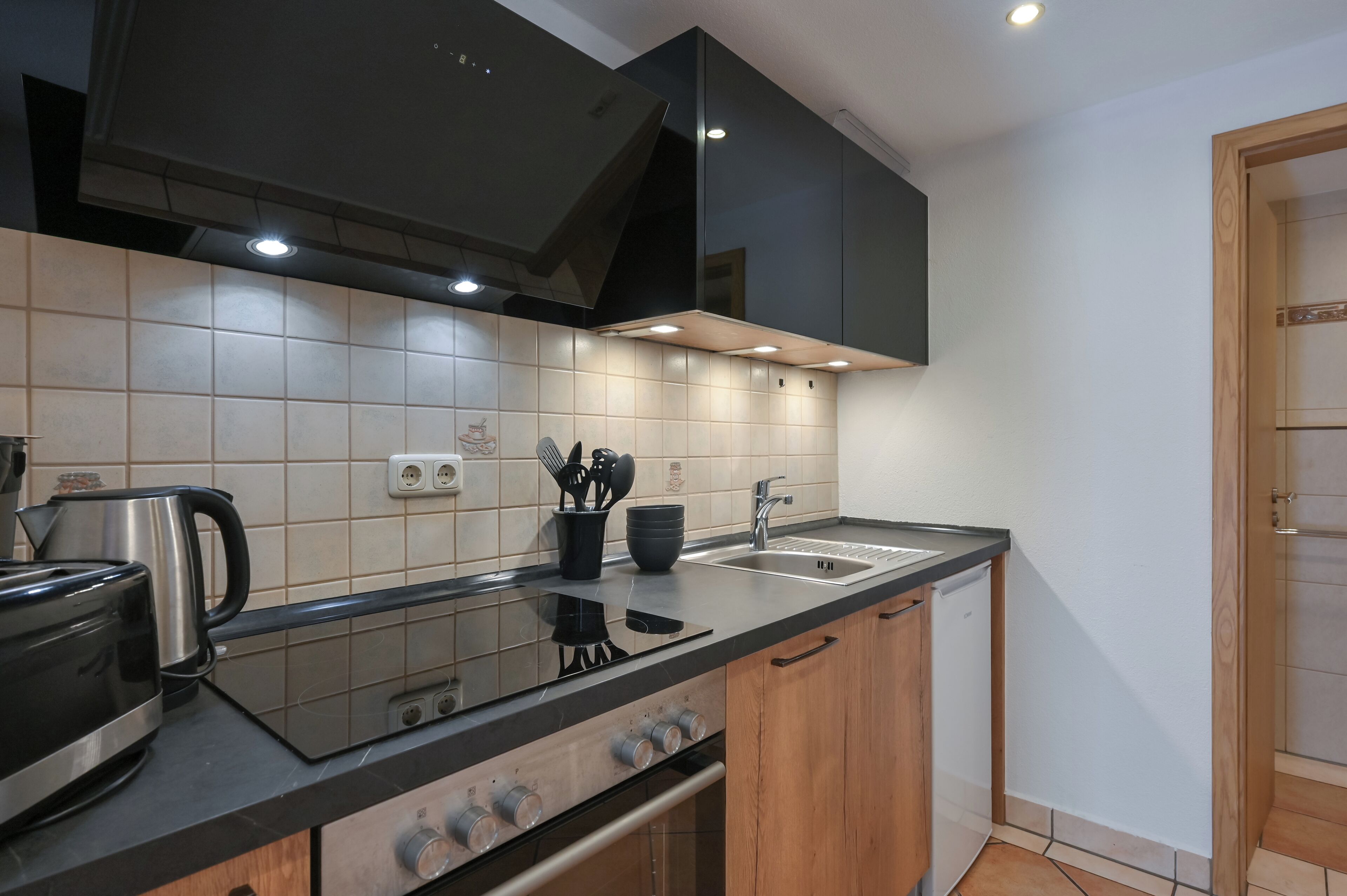 Una cocina moderna con encimera negra, electrodomésticos de acero inoxidable y armarios de madera.