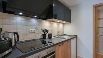 Una cocina moderna con encimera negra, electrodomésticos de acero inoxidable y armarios de madera.