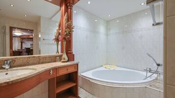 Ein modernes Badezimmer mit einer großen Badewanne, einem Waschbecken mit Spiegel und einer dekorativen Vase.