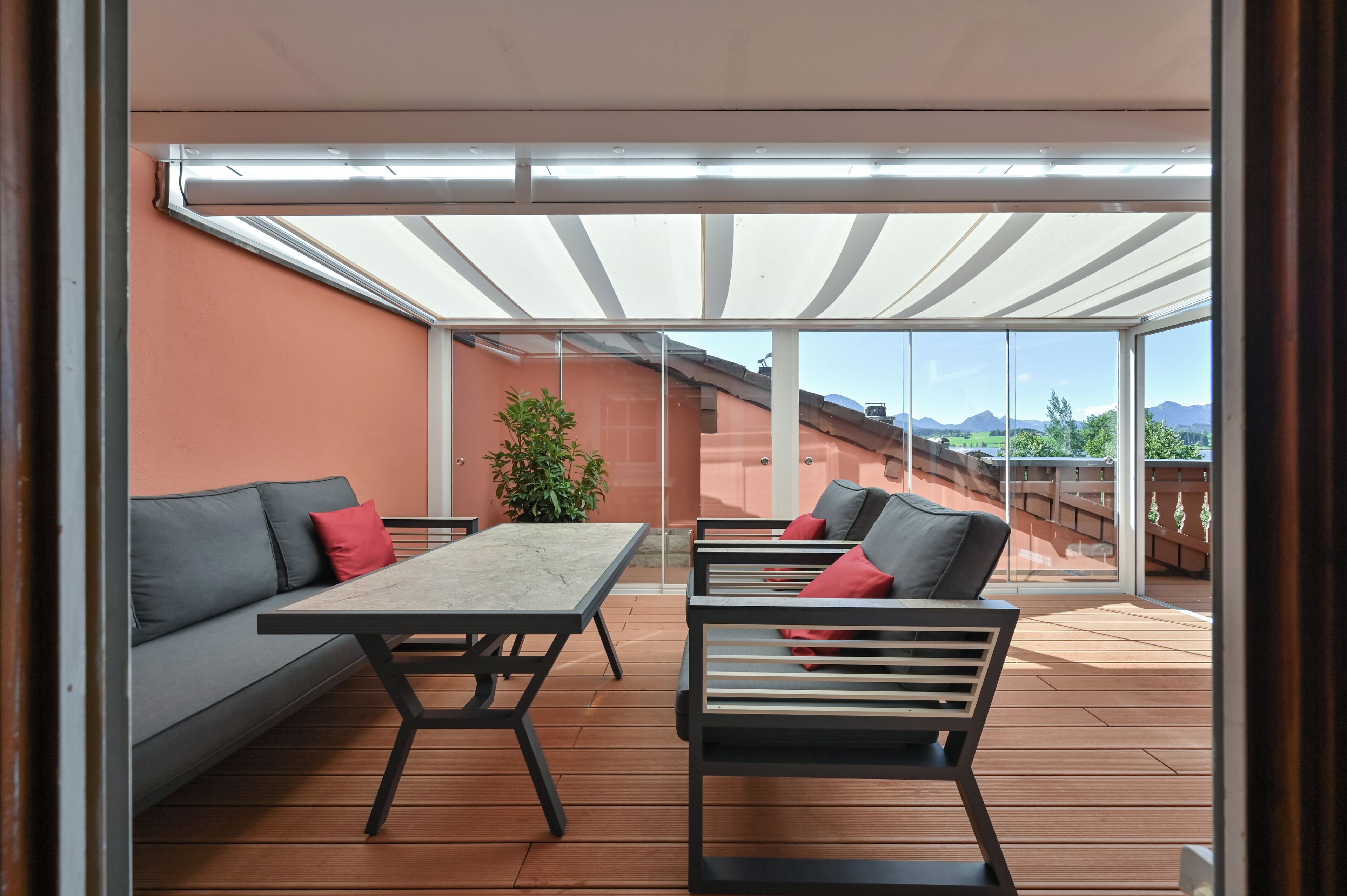 Une terrasse extérieure avec une table et deux chaises, un canapé et une plante en pot.