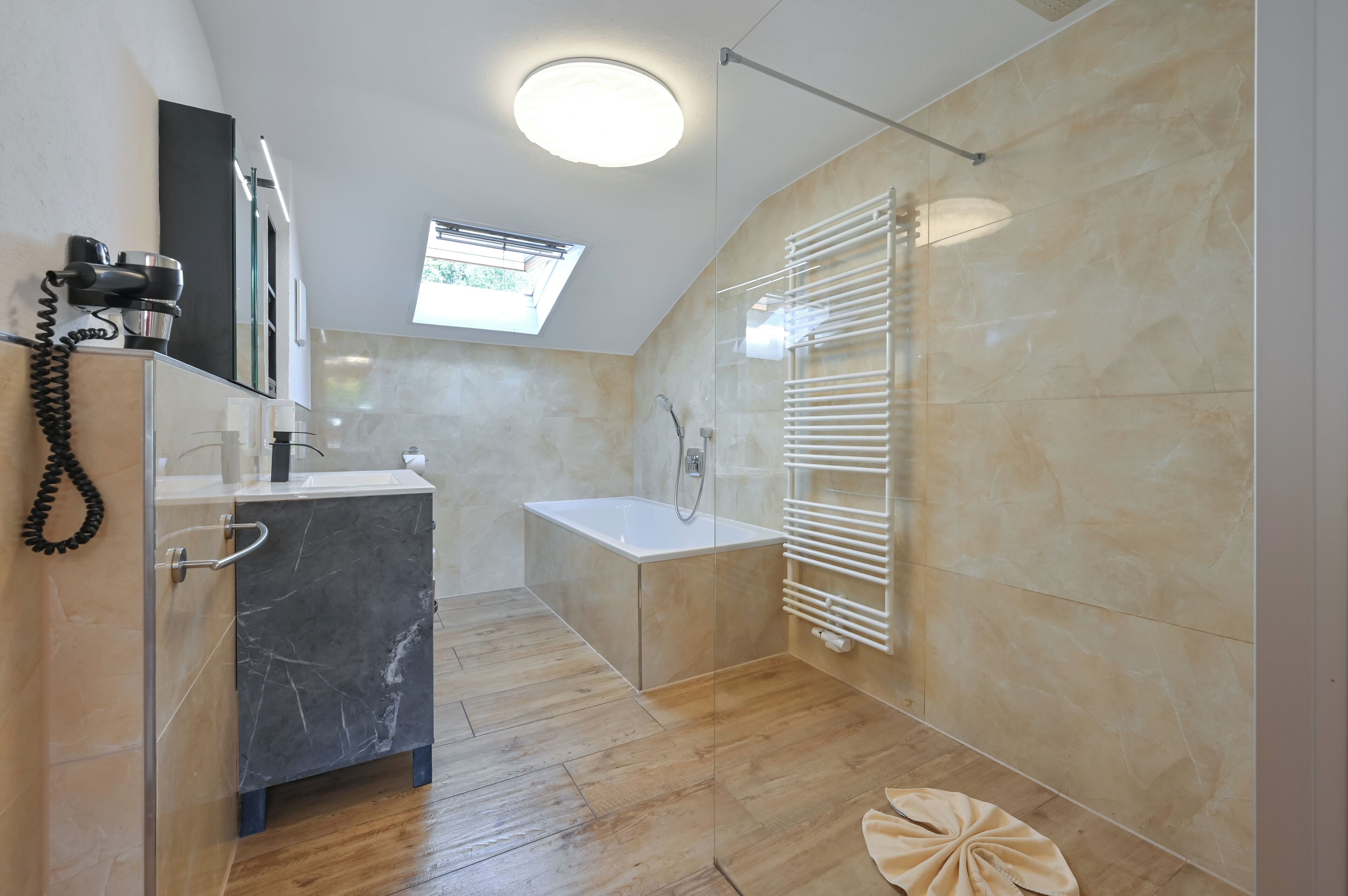 Un baño moderno con ducha, bañera y tocador con encimera de mármol.