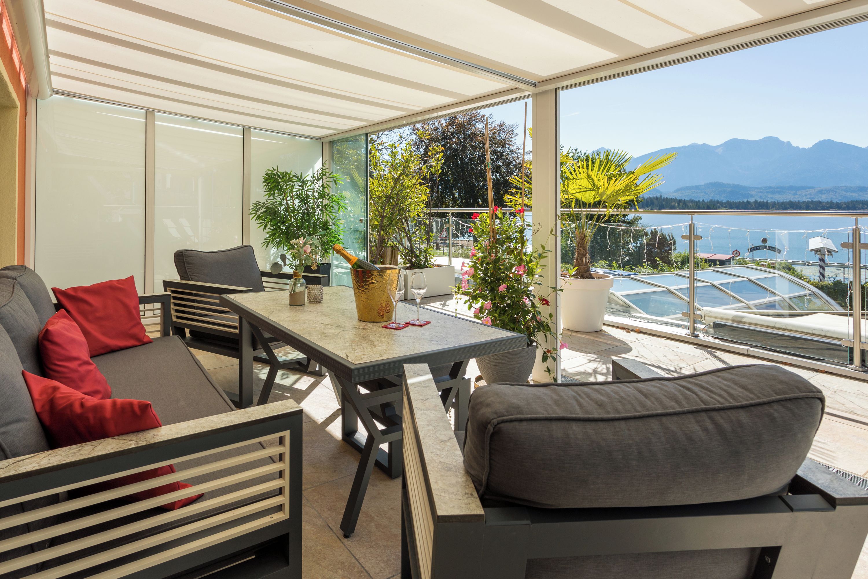 Ein sonniger Balkon mit Tisch, St ühlen und Topfpflanzen.