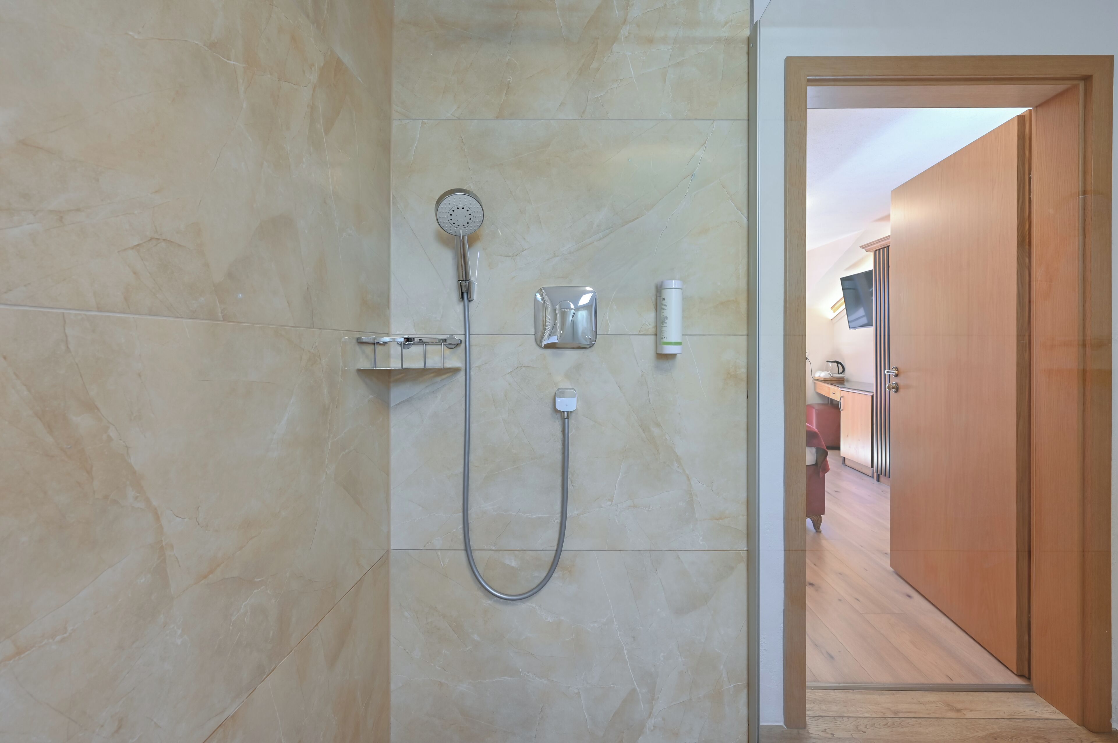 A bathroom with a shower, a soap dispenser, and a towel rack.