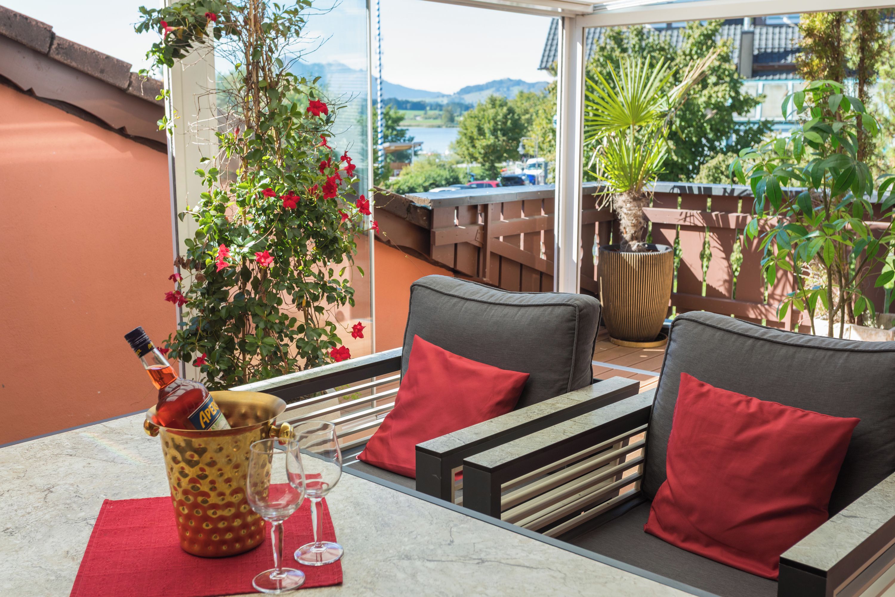 Eine Terrasse mit Tisch, zwei Stühlen, einer Flasche Aperitif und einem Weinglas.