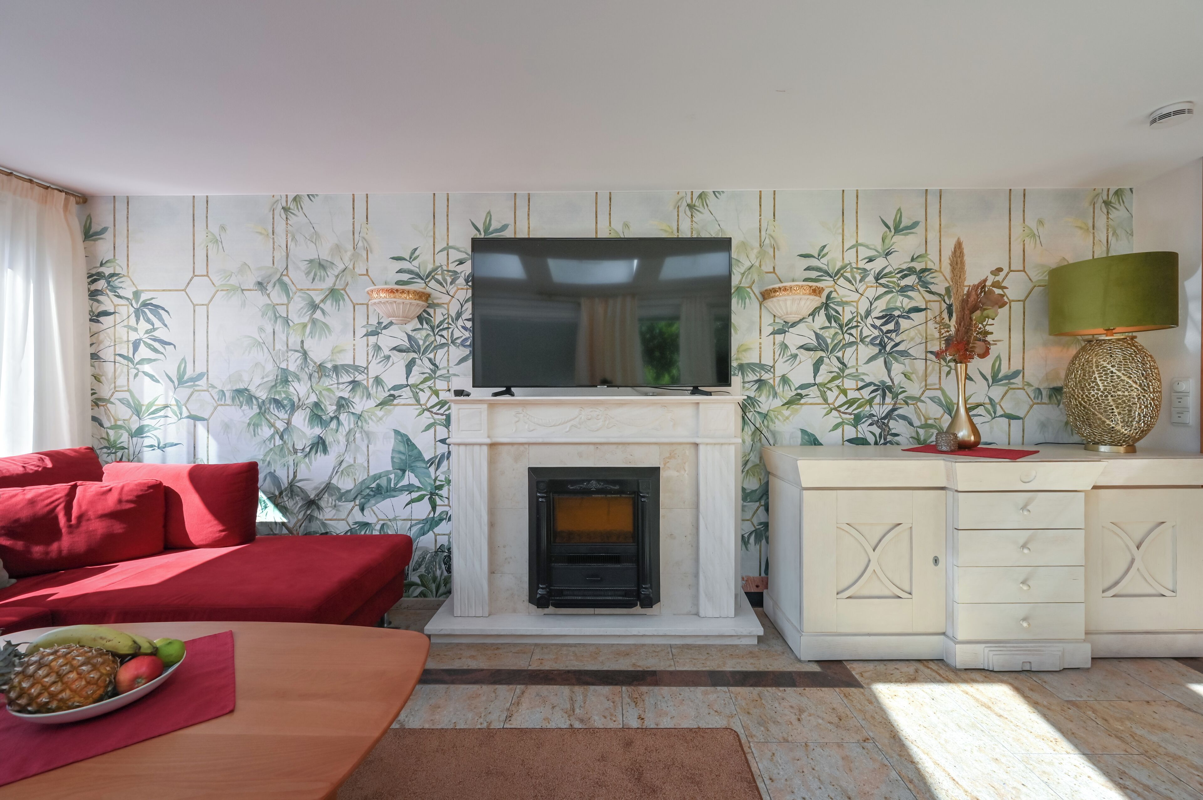 A living room with a fireplace, a television, and a dining area with fruit.