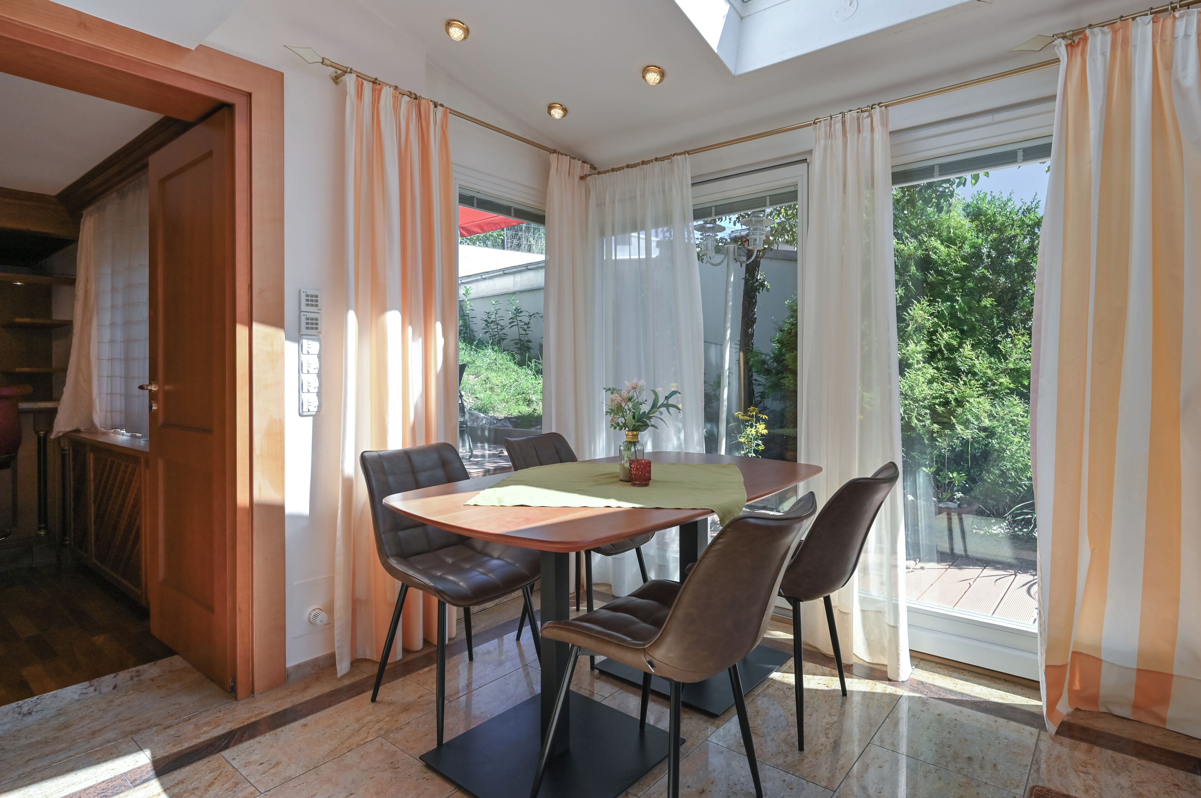 Comedor con una mesa de madera, cuatro sillas y vistas a la vegetación exterior.