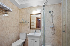 A bathroom with a toilet, sink, mirror, shower, and towel rack. - Apartamenty Furta Dominikańska (Sandomierz)