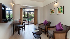 A modern living room with a flat-screen TV, a dining table, and two wicker chairs with cushions. - So My Resort (Calangute)