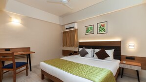 A hotel room with a bed, a desk, a chair, an air conditioning unit, and two wall-mounted lights. - So My Resort (Calangute)