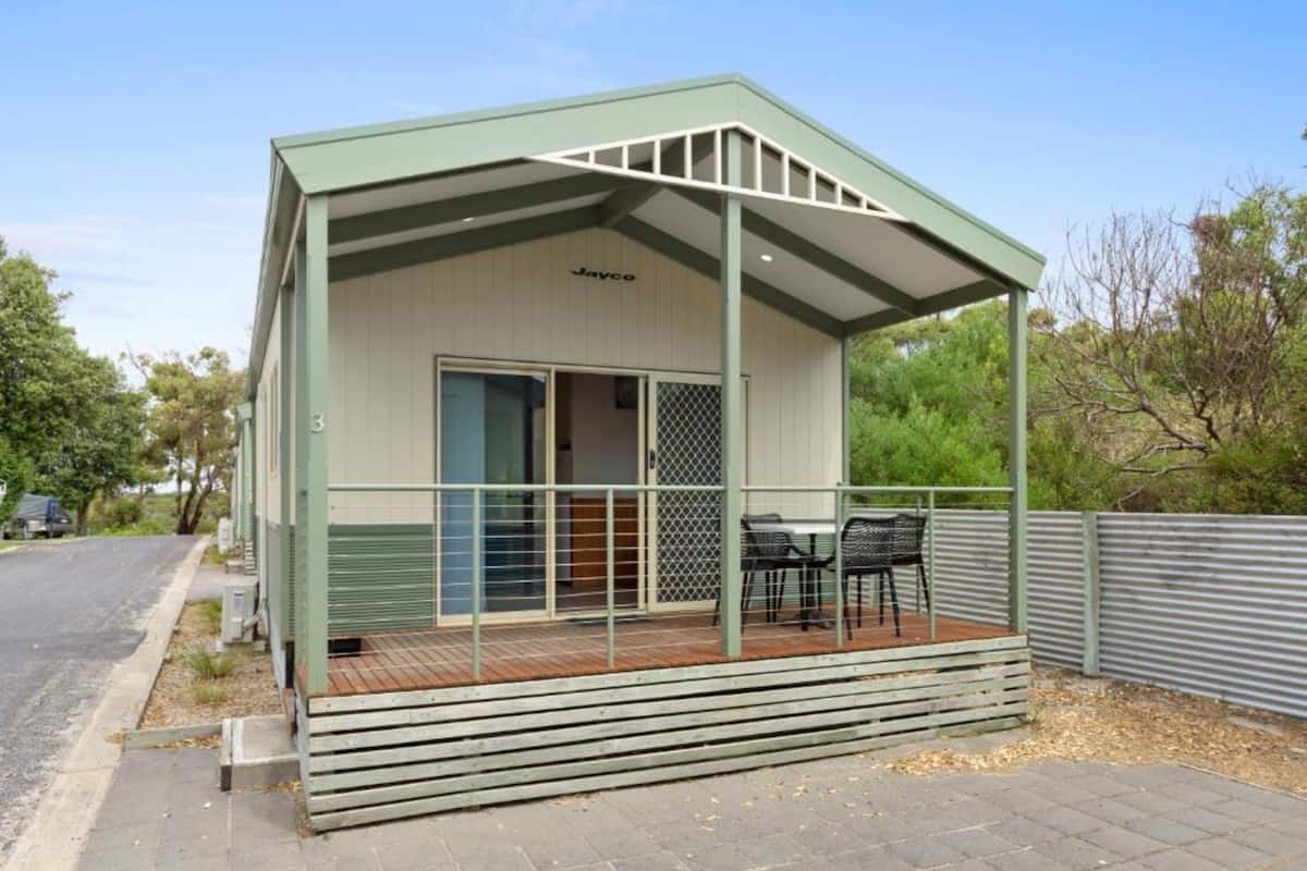 A small, single-story building with a covered porch and a table and chairs.